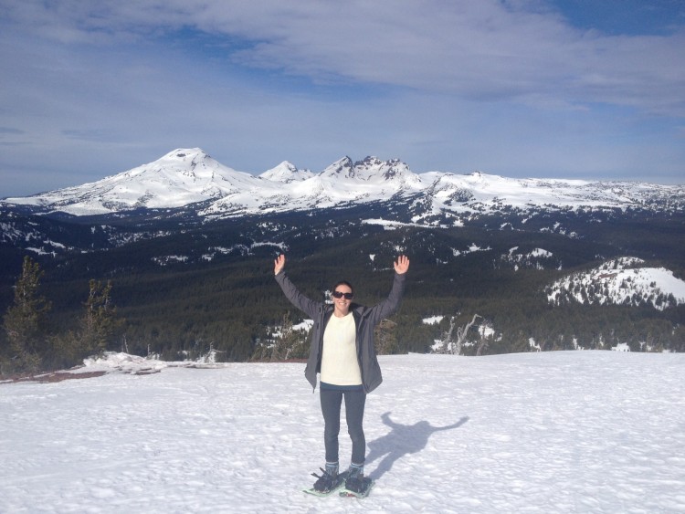 woman holding hands up while snowshoeing