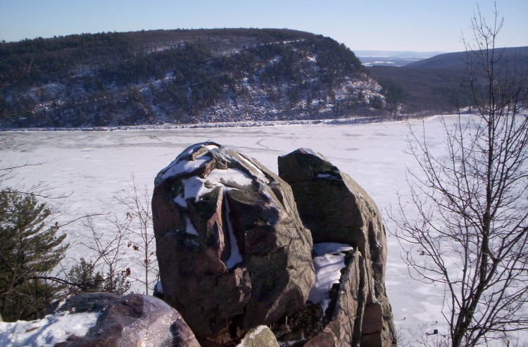 rock formation with snow and iced over lake and hill in background