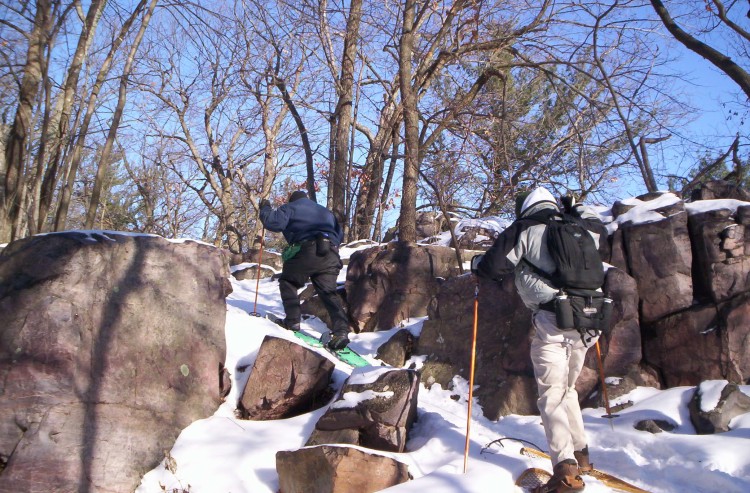 snowshoers climbing hill surrounded by rocks