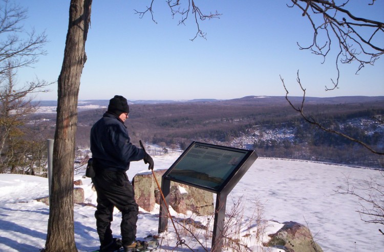 man observing info sign at Ice Age Trail with view overlooking a frozen lake