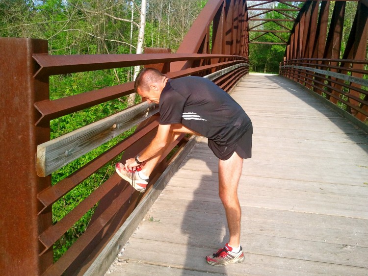 man tying his shoe while on a run