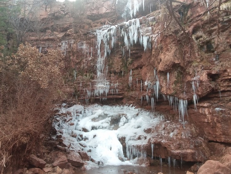 frozen waterfall surrounded by rock and trees