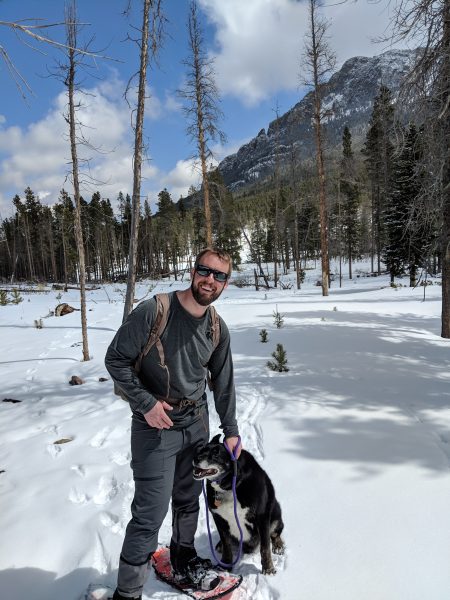 dog and person on snowshoes smiling with trees in background