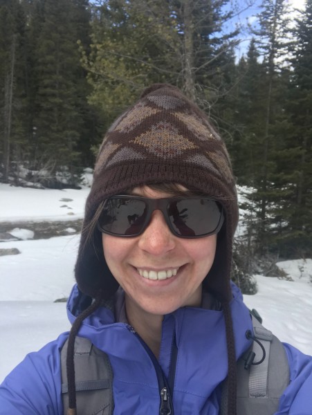 winter skin care tips: close up of woman smiling while wearing hat and sunglasses in winter