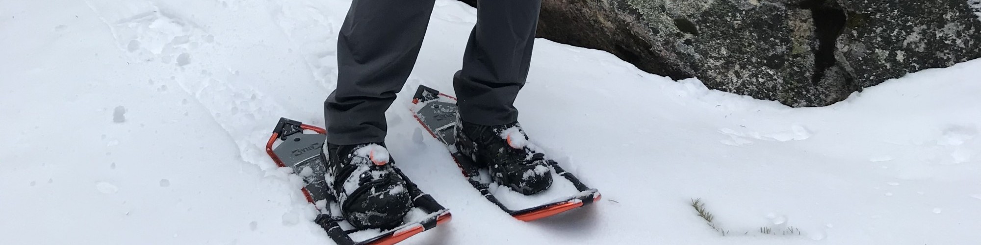 man in snowshoes pointing down towards snow