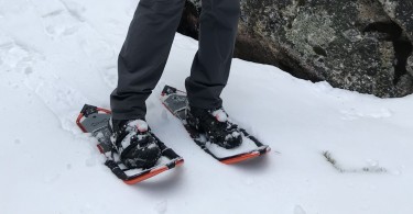man in snowshoes pointing down towards snow