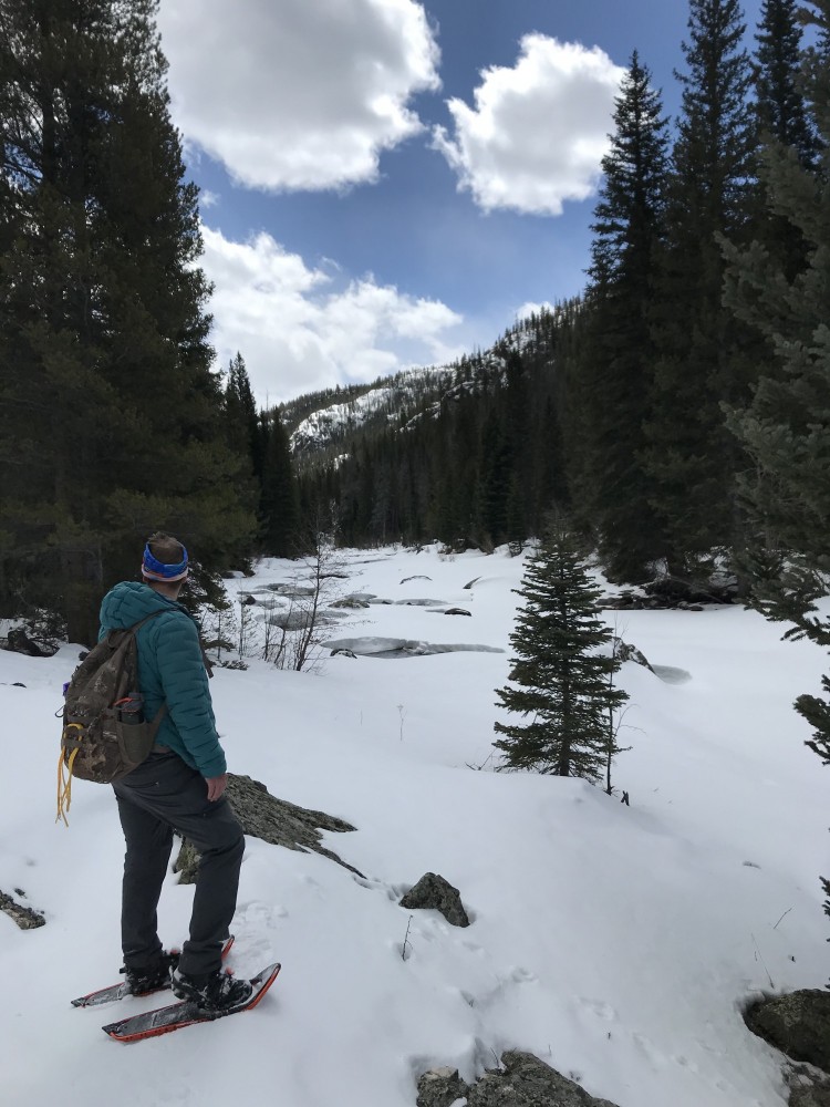 man with snowshoes looking at river