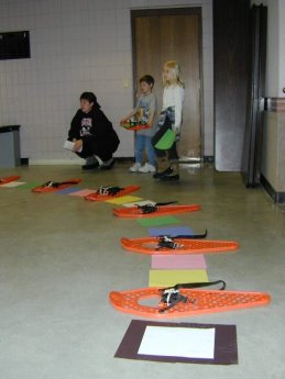 kids standing indoors with snowshoes lined up