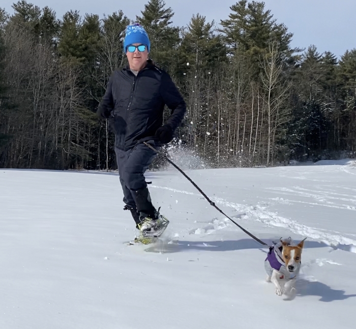 man snowshoeing with his dog