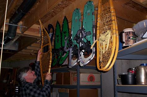 snowshoe storage: man hanging up snowshoes in garage for storage
