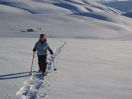 woman snowshoeing in New Zealand with poles with snow covered hills in background