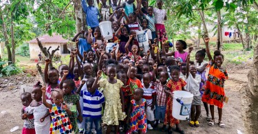 group of children in Liberia with hands in the air and holding Sawyer filters