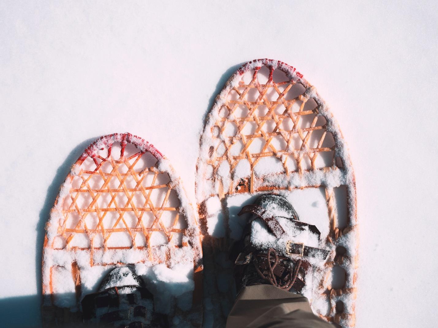 traditional snowshoes with feet in them on snow