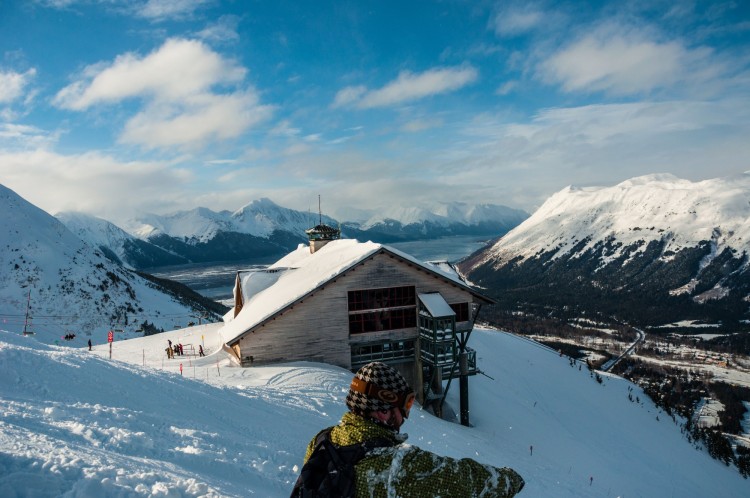 man sitting on on snowy hill at Alyeska Resort overlooking Chugach mountains