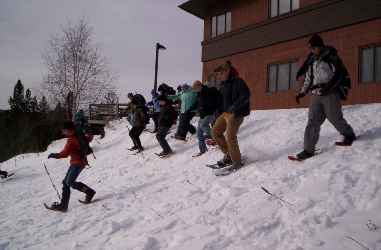 students going downhill on snowshoes