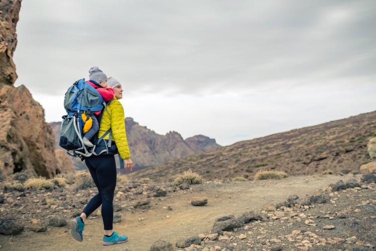 woman with baby in backpack on hike in fall