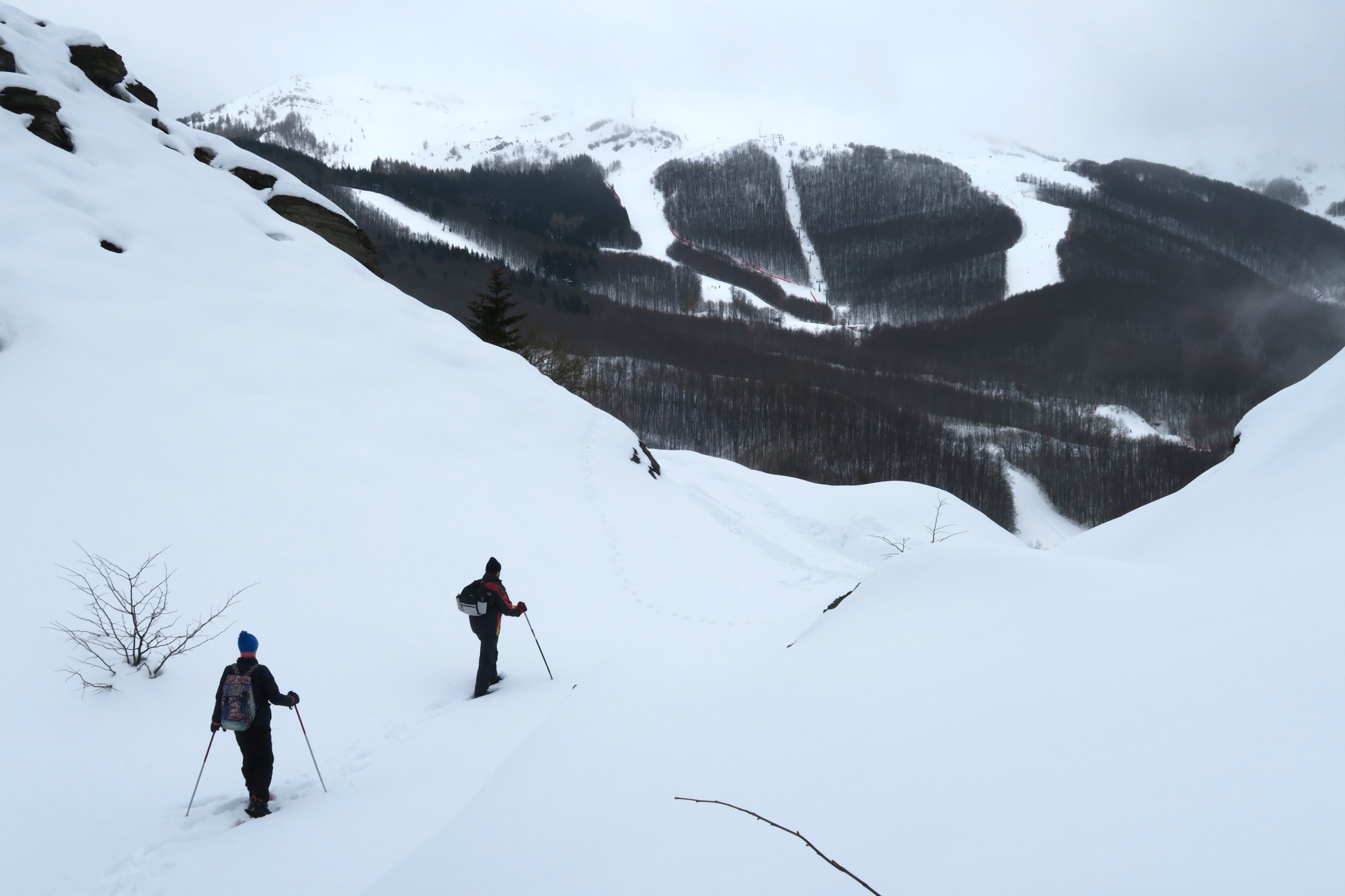 two snowshoers walking through hilly landscape