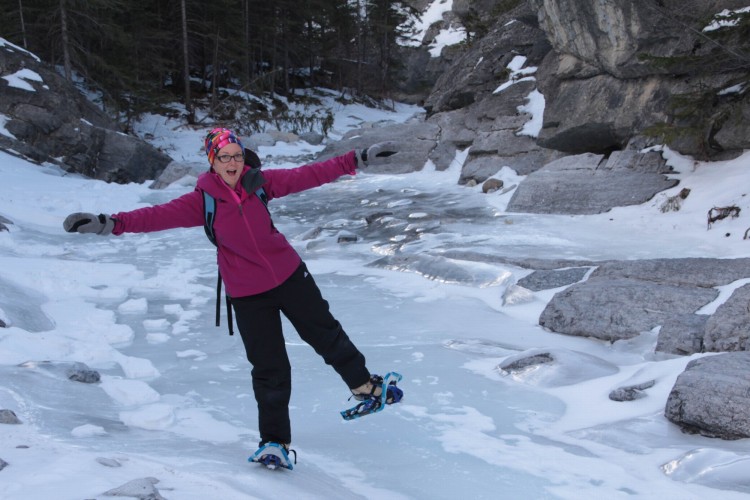 woman wearing snowshoes while crossing river