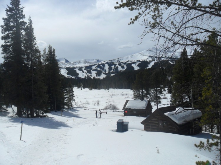view of snowy log buildings and mountains with people in background