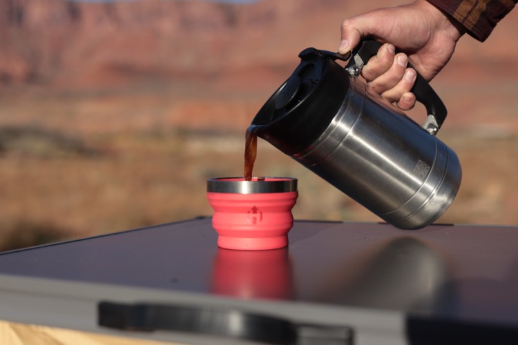 winter camping cooking gear: Bru Trek Press pouring coffee into mug on outdoor table