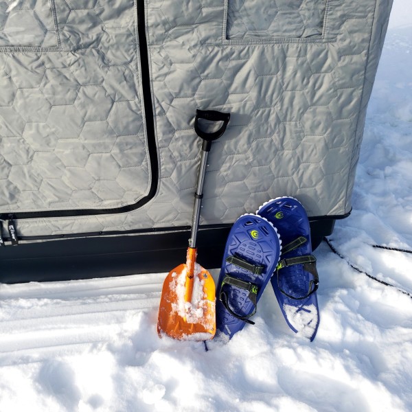 snow shovel and snowshoes leaning next to ice shanty
