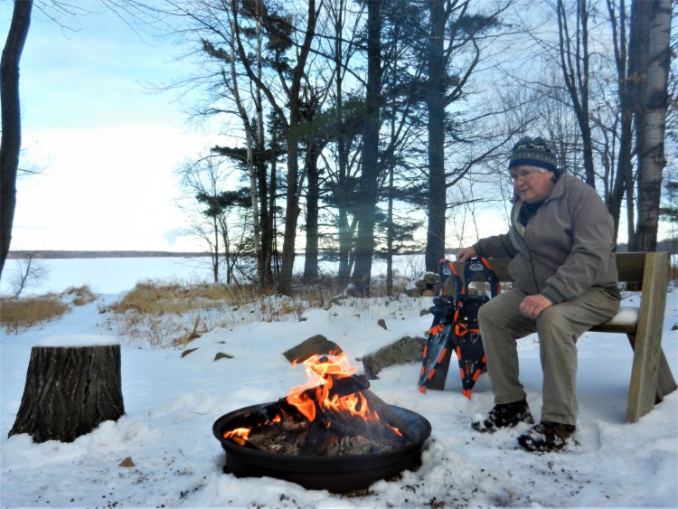 man with snowshoes near a winter campfire