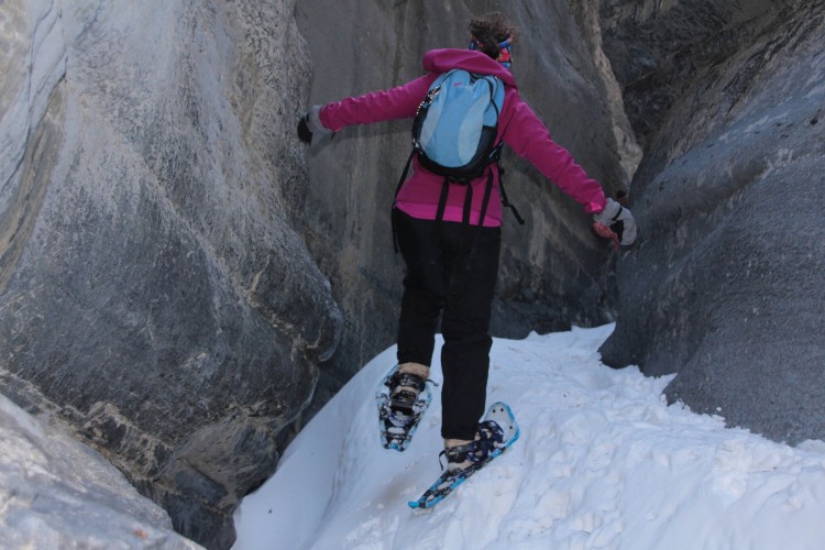 woman walking up a snowy will with large rocks surrounding the person