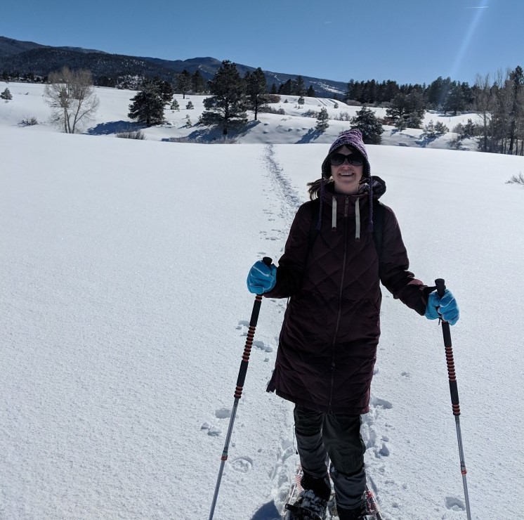 woman in long jacket on snowshoes with blue sky - Chama NM