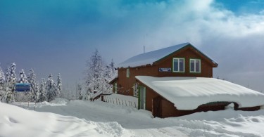 mountain hut covered in snow with blue sky