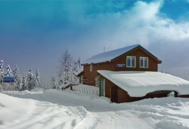 mountain hut covered in snow with blue sky