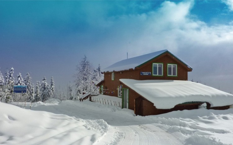 mountain hut covered in snow with blue sky