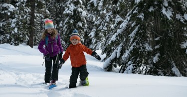 kids on snow with trees in background wearing Crescent Moon snowshoes