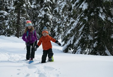kids on snow with trees in background wearing Crescent Moon snowshoes