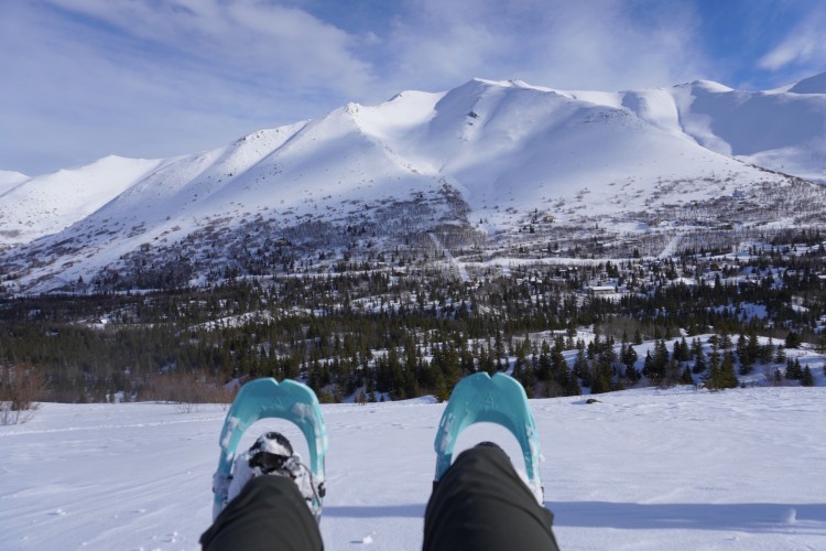 snowshoes, in front of a snow-capped mountain