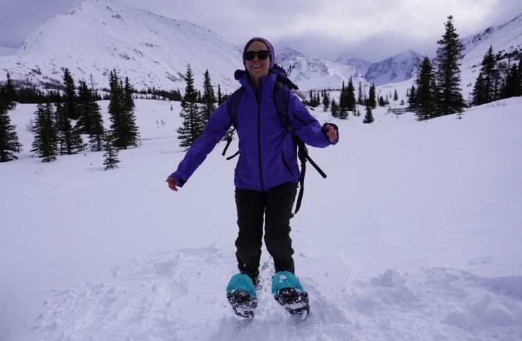 person jumping in Wildhorn snowshoes with snowy mountains in background