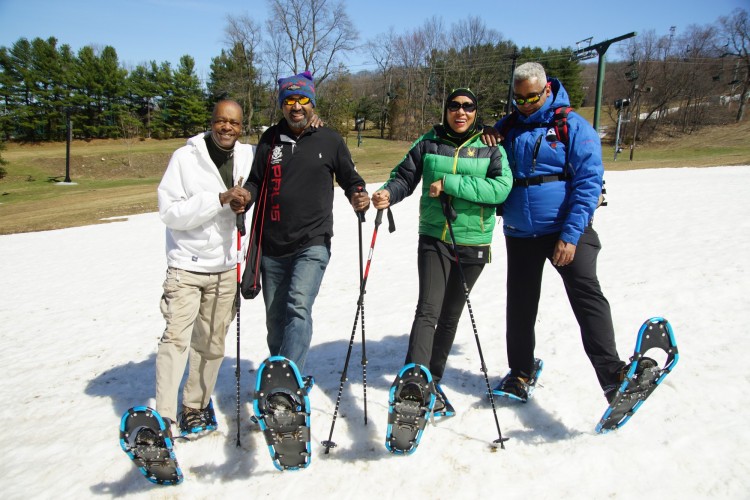 four snowshoers with snowshoes raised on snow at NBS snowshoe event