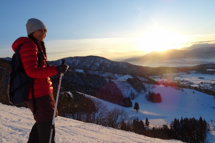 woman on snowshoes on mountain with sunset