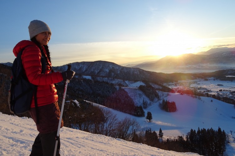 woman on snowshoes on mountain with sunset
