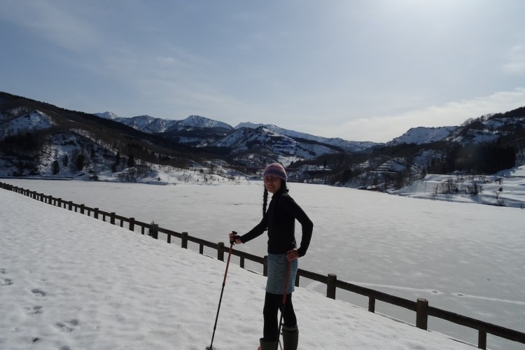 Sanjo, Niigata, Japan: person with snowshoes and poles on snowy route with mountains in background at Otani Dam