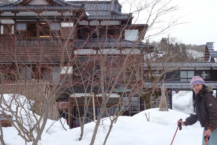 woman in front of inn with trees and snow in foreground