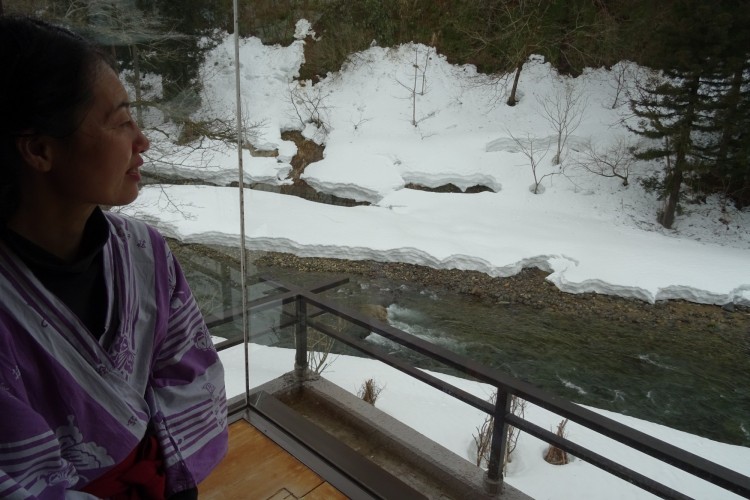 woman looking out from balcony at river and snow