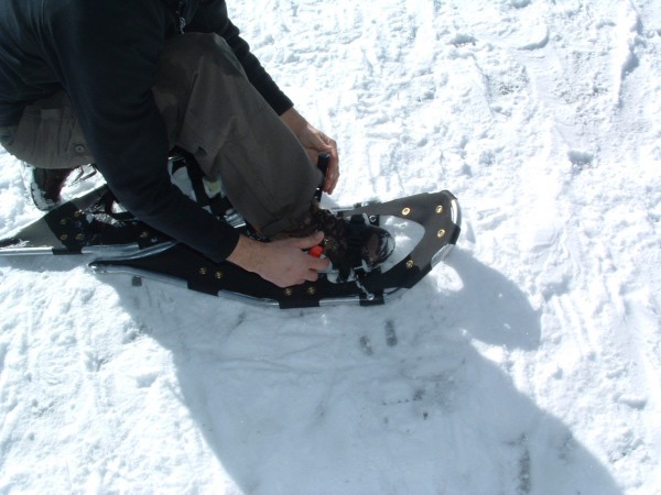 snowshoeing tips: person putting on their snowshoe