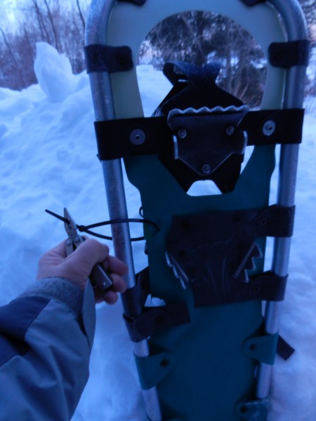 snowshoe repair kit: close up of person use a plastic tie to attach the decking to the snowshoe frame