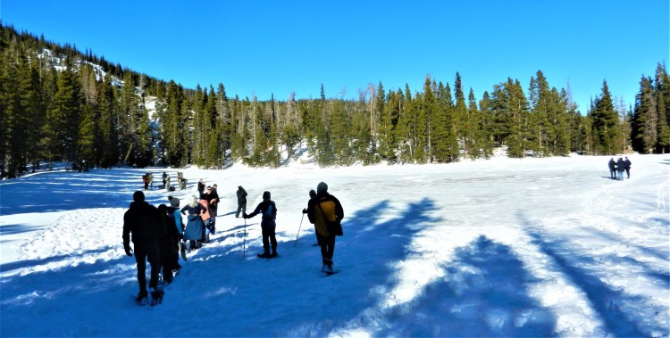 tips for rmnp winter: groups of people gathered near a snow covered lake