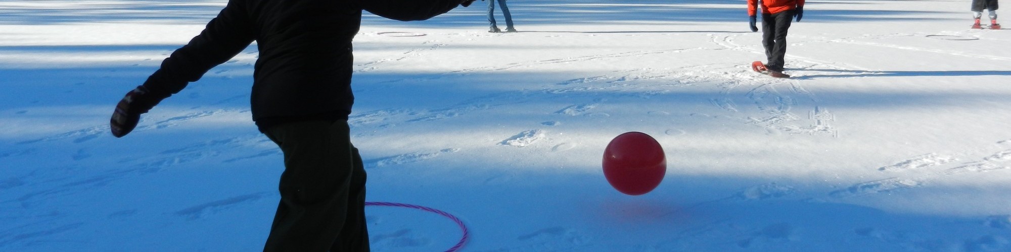 person on snowshoes ready to kick a ball in winter snowshoe game