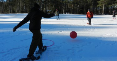 person on snowshoes ready to kick a ball in winter snowshoe game