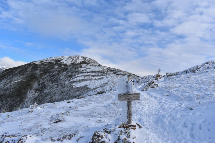 snowy, cold mountain peak with blue sky and clouds in background