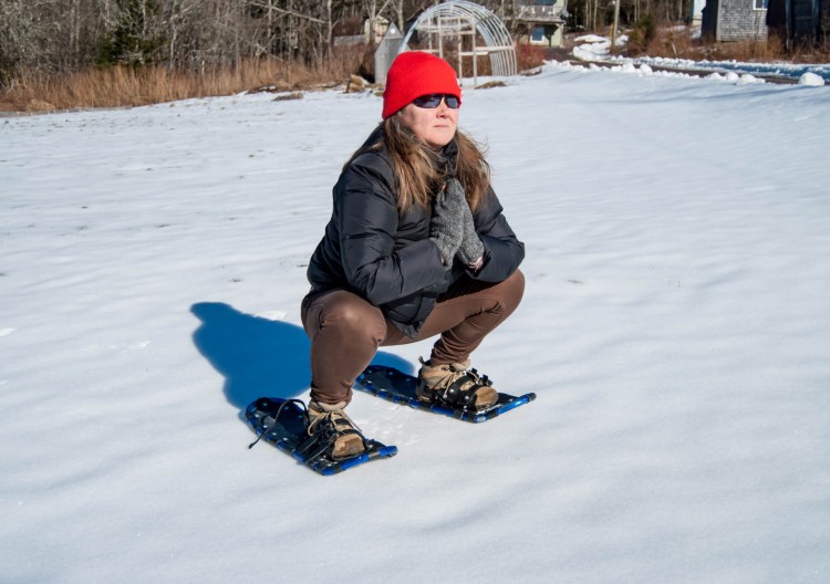 woman squatting on snowshoes in a yoga pose