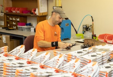 person next to many pairs of snowshoes in factory