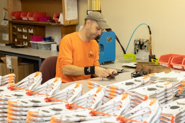 person next to many pairs of snowshoes in factory